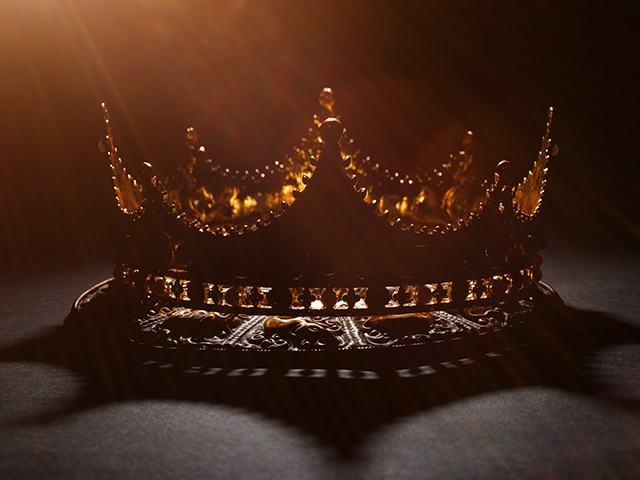 a light shines on a gold crown against a dark background